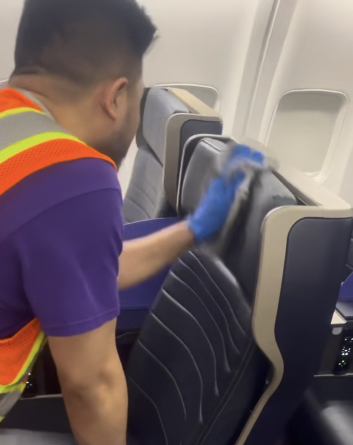 Flightline technician caring for an aircraft seat, with gloved hands on the headrest and armrest
